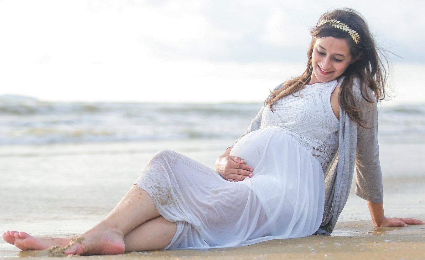 Serene maternity moment as an expecting mother embraces her journey by the sea.